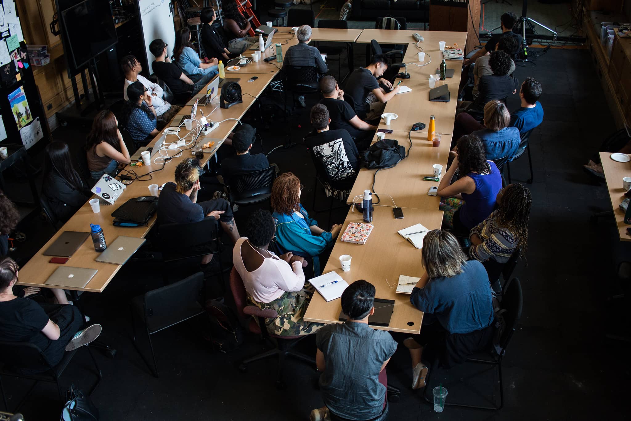 Participants sitting around a large U shaped table looking towards the front of the classroom