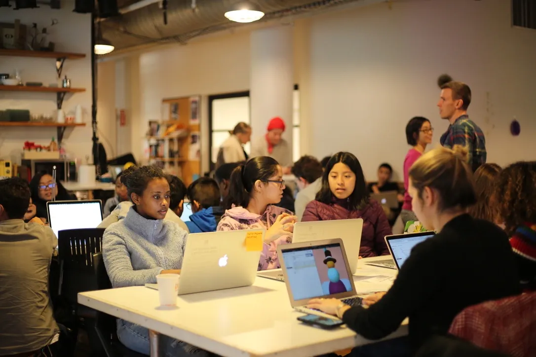 p5.js workshop participants coding while showing their projects on screen.